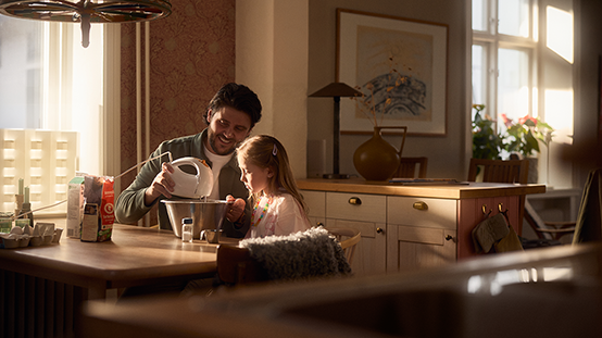 Ett barn och en pappa som använder en elvisp vid ett bord