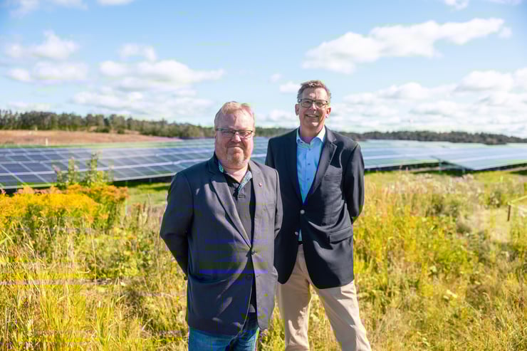Kommunstyrelsens ordförande i Mölndal Stefan Gustafsson och vd Mölndal Energi Christian Schwartz står framför Solpark Kikås med solpaneler i bakgrunden. 