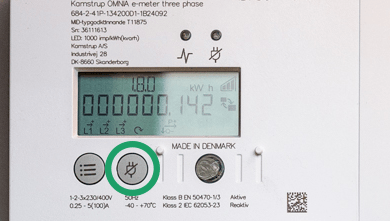 Inzoomad bild på en elmätare, med knappen för avstängning inringad, den har en bild med en överstruken stickkontakt på sig. 