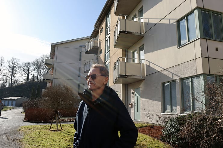 Göran Eriksson står i solen utanför ett lägenhetshus i brf Åbybergsparken